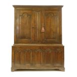 An 18th century oak bacon cupboard, the ogee moulded cornice over two cupboard doors with carved