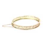 A gold pierced oval hinged flat section bangle