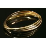 An Italian three colour gold hollow Russian wedding ring style hinged bangle