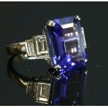 A platinum single stone tanzanite ring with diamond set shoulders,