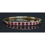 A 9ct gold ruby and diamond hinged bangle,