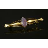 A gold single stone black opal bar brooch