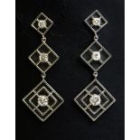 A pair of white gold three stone diamond drop earrings,