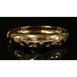 An 18ct gold diamond set oval hinged bangle,