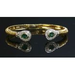An 18ct two colour gold emerald and diamond hinged torque bangle,