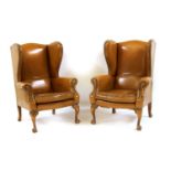 A pair of tan leather wingback armchairs