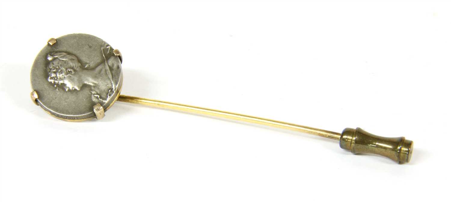 A Continental gold stick pin with an Art Nouveau medallion claw set in the top