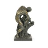 A large bronze figure of an athlete splitting a tree trunk,