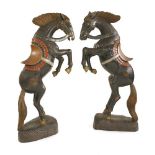 A pair of large carved wooden and polychrome decorated prancing horses,