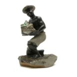 A South American hardstone sculpture of an agricultural worker wearing a hat and carrying a rock,