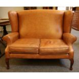 A modern tan brown leather wing back two seater sofa,
