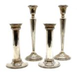 A pair of white metal candlesticks of column form on circular beadwork foot,