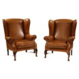 A pair of modern tan brown leather wing back armchairs