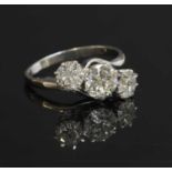 A platinum three stone diamond crossover ring,