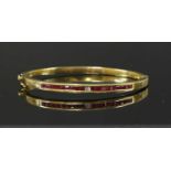 A gold diamond and ruby set hinged bangle,