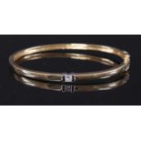 An 18ct two colour gold, single stone diamond hinged bangle,