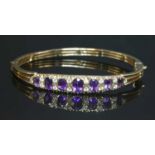 A 9ct gold amethyst and diamond hinged bangle,