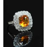 A white gold orange sapphire and diamond cushion shaped cluster ring,