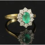 An 18ct gold emerald and diamond oval cluster ring,