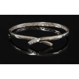 An 18ct white gold diamond set crossover bangle,