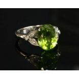 An 18ct white gold single stone peridot ring with diamond set shoulders,