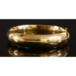 A hollow 'D' section hinged gold bangle,