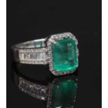 A white gold emerald and diamond cluster ring,