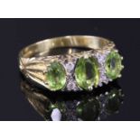 An 18ct gold three stone graduated peridot carved head style ring,