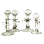 A group of four open flame 'lacemaker' type glass oil lamps,