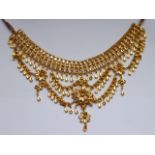 An Indian yellow-metal fringe necklace on a further cord necklace,