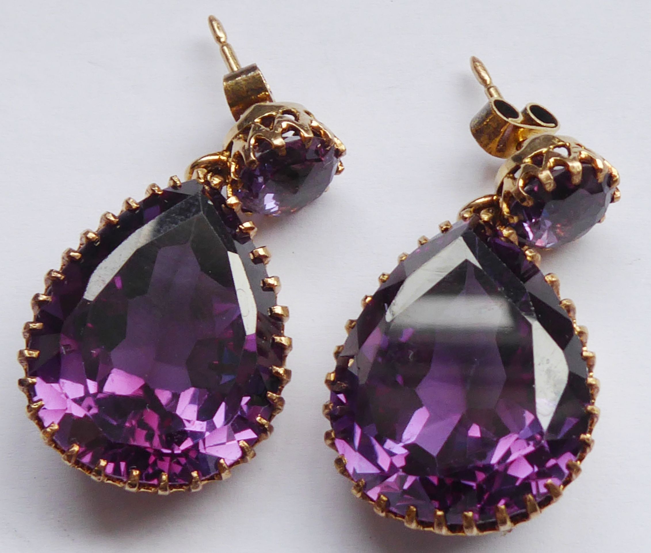 A pair of yellow metal drop earrings set with large pear-shaped hand-cut amethysts