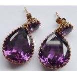 A pair of yellow metal drop earrings set with large pear-shaped hand-cut amethysts