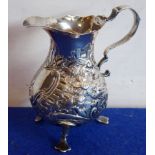 A mid-18th century hallmarked silver baluster-shaped cream jug with later repoussé style decoration,