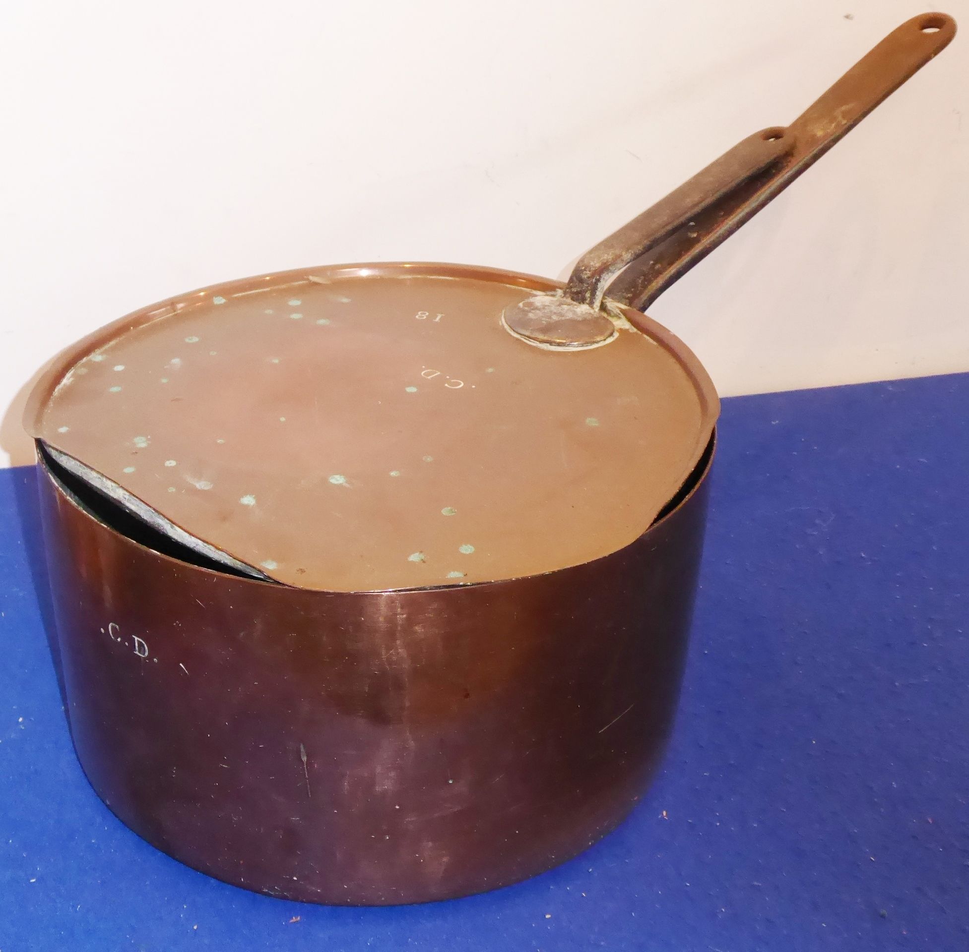 A large and heavy circular long-handled copper saucepan; its lid also with iron handle,