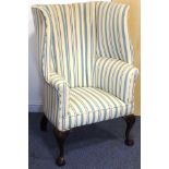 A 19th century (in 18th century style) upholstered wing-back armchair;