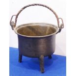 A 17th century bronze cooking pot with wrythern iron handle and raised on three tapering triangular