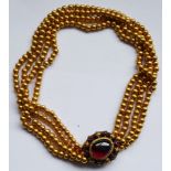 A four-row threaded yellow metal Continental necklace with a cabouchon garnet cluster snap, approx.