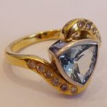 An 18-carat gold Art Deco style ring set with a central aquamarine of good colour surrounded by