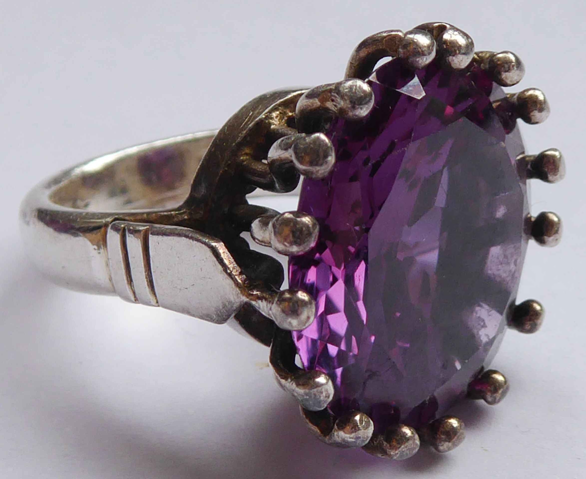 A white metal and single round amethyst claw-set ring