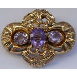 A yellow metal brooch set with three hand-cut oval amethyst-type stones