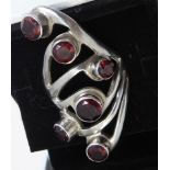 A modernist silver (marked 925) ring of pierced section and set with six hand-cut red stones in