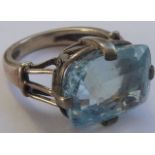 A white metal ring set with a large hand-cut light-blue stone (possibly aquamarine/zircon),