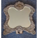 A large silver-framed easel-style dressing table mirror; central shaped vacant cartouche (dent)