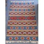 A tribal-style flat-weave rug, varying horizontal bands with predominantly repeating lozenge designs