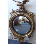 A large late Regency period giltwood circular convex wallhanging girandole; surmounted with a carved