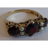 A lady's ornate yellow-gold (marked 9ct) dress ring centrally set with a hand-cut garnet flanked