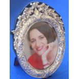 An ornate oval-framed modern silver photo frame