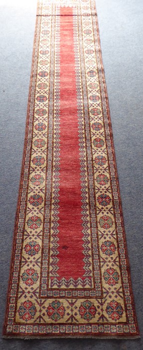 A hand-knotted Afghan Kazak-style runner; central red ground rectangle surrounded by three