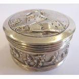 A small early-20th century white-metal (probably Dutch) circular box and cover, the lid decorated
