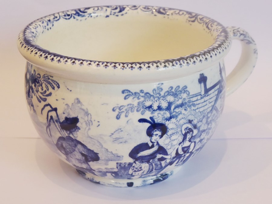 An early 19th century pottery bowl, blue transfer-decorated with figures outside a country